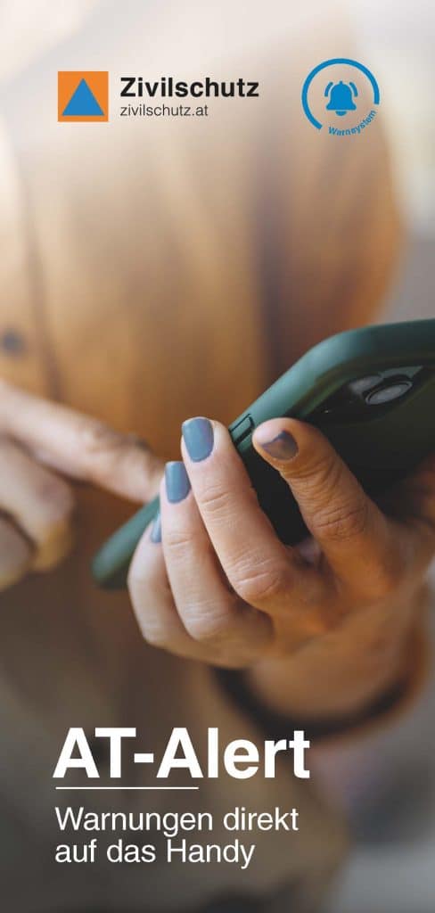 Eine Person mit lackierten Nägeln benutzt ein Smartphone. Das Bild zeigt die Logos von Zivilschutz und Warnsystem sowie den Text: "AT-Alert Warnungen direkt auf das Handy.".